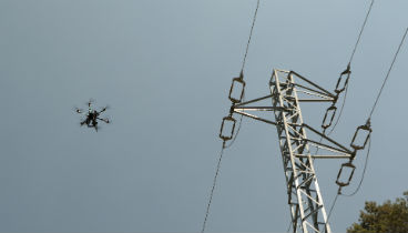Drones volando sobre torres eléctricas durante el mantenimiento de las redes